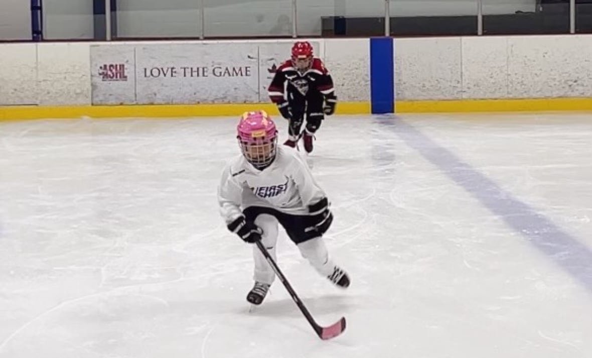 Two youth hockey players skate.
