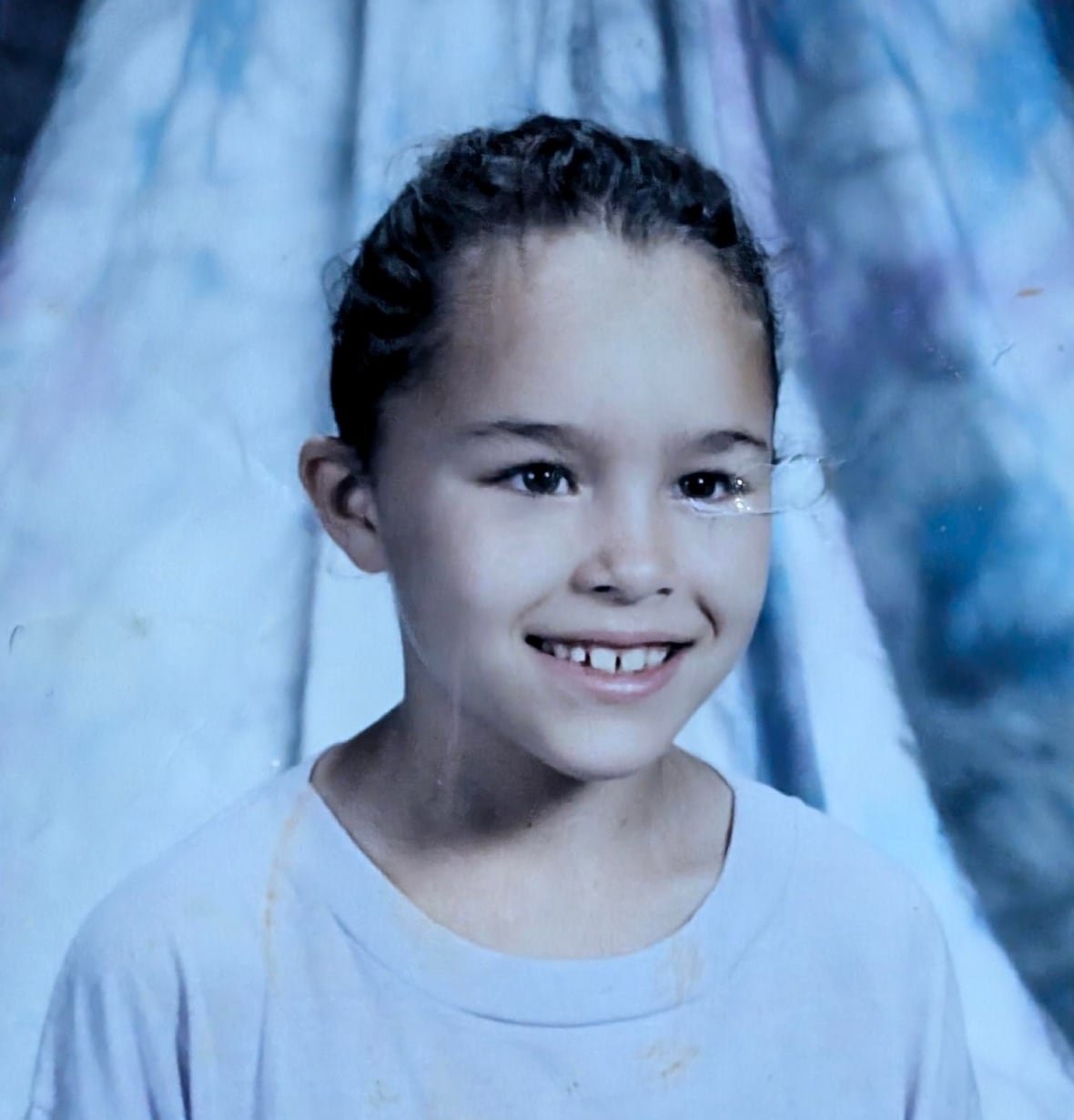 A young girl smiles for a posed photo.