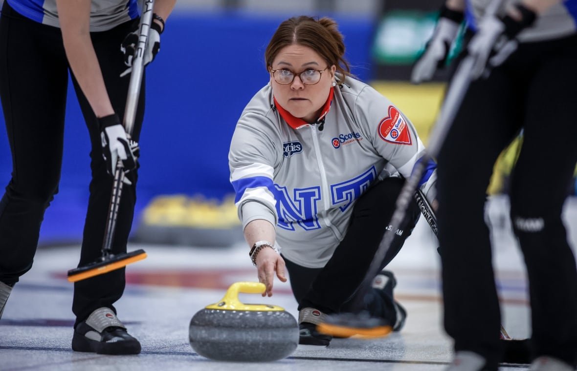 A female curling skip makes a shot.
