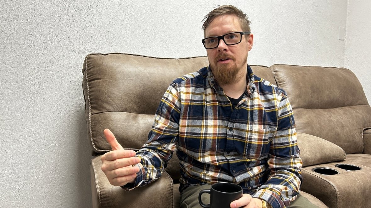 kevin-purdue Man in plaid sits on a couch.