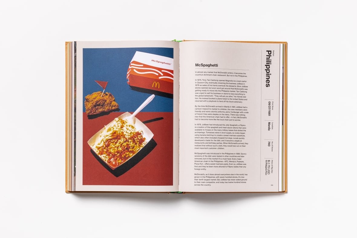 mcspaghetti-mcatlas A book open and laid flat. On the left page is a large photo of a McDonald's container full of Spaghetti. On right is a page of text detailing the McSpaghetti's history.