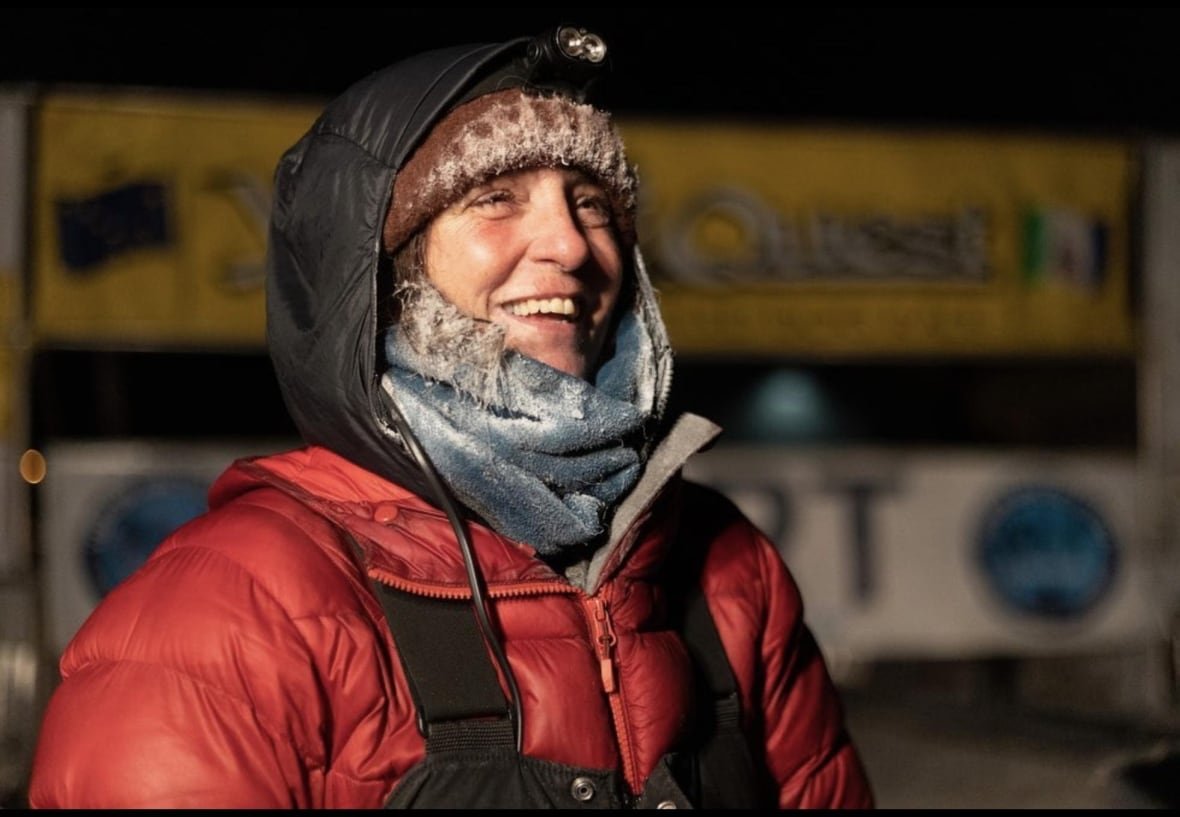 michelle-phillips A smiling woman in a headlamp and a parka stands outside in the dark.