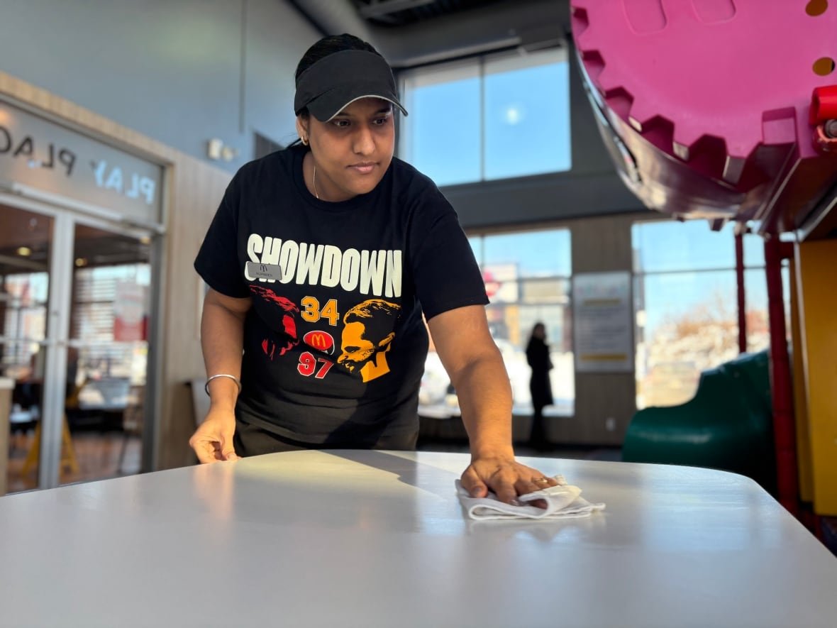 Rupinder Kaur wipes a table at McDonalds with a cloth.