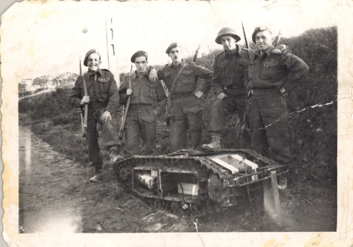 A group of Canadian soldiers stand next to a captured German tracked mine in 1944.