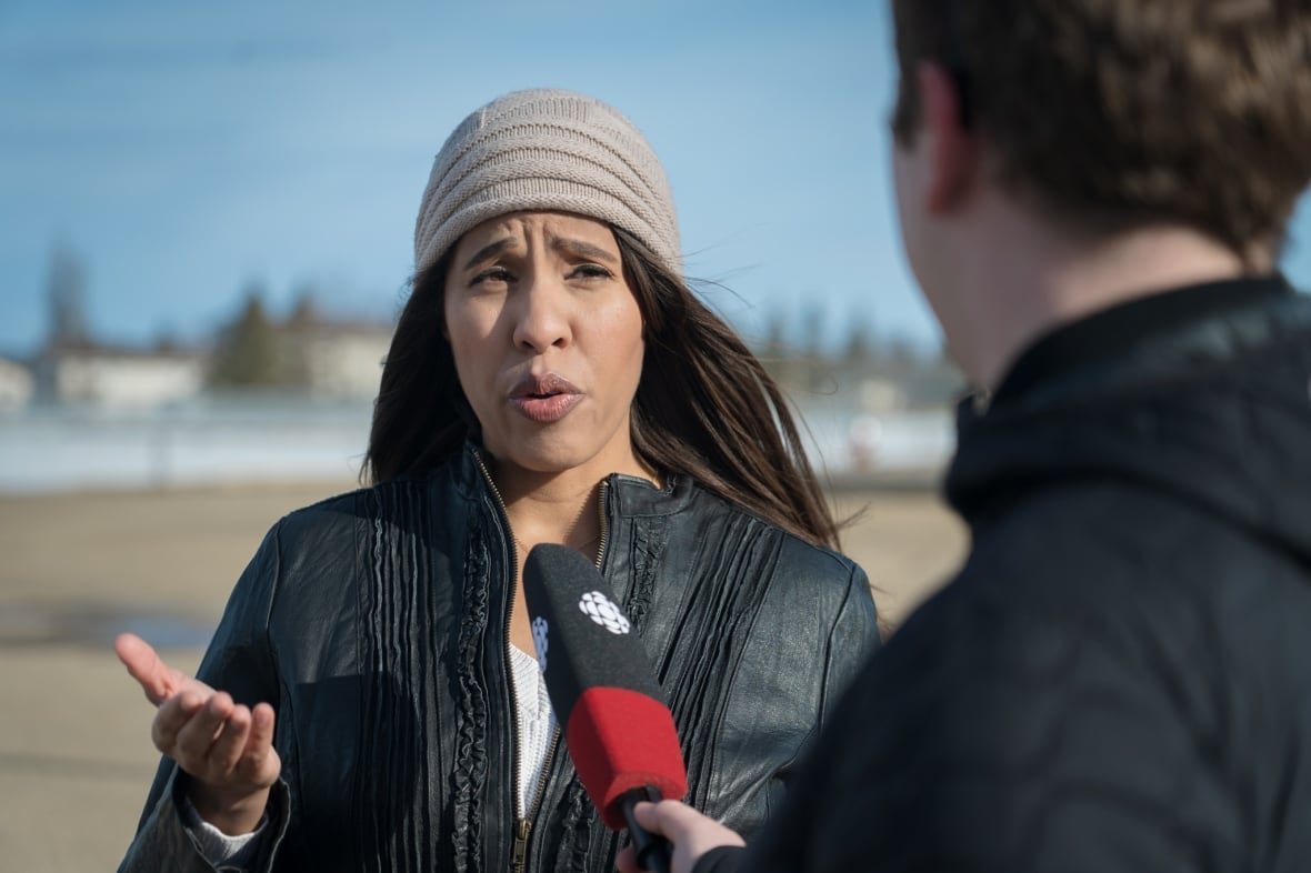 stephanie-bakker A woman wears a white t-shirt with a black jacket. She speaks to a reporter during an interview.