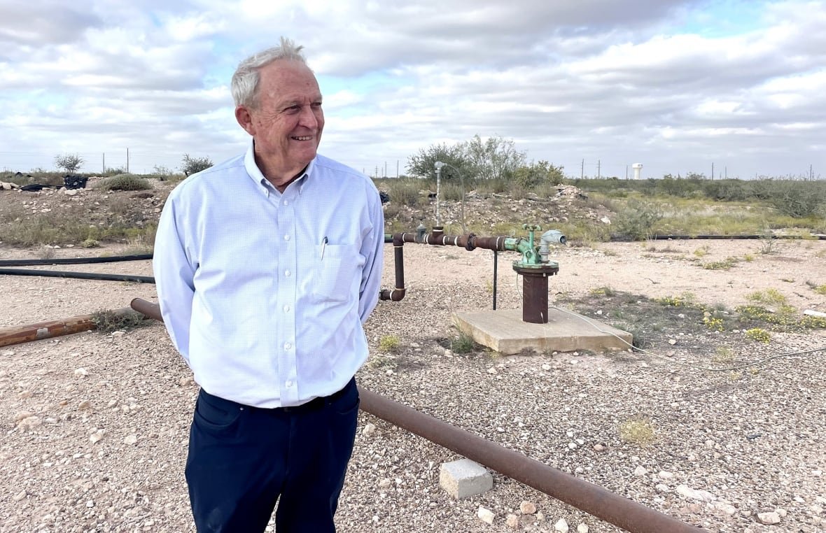 A man in a white shirt stands over pipes.