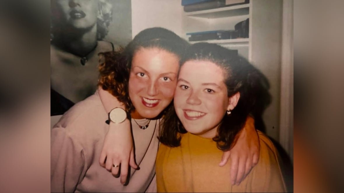 Two teenage girls have their arms around each other and smile for the camera.