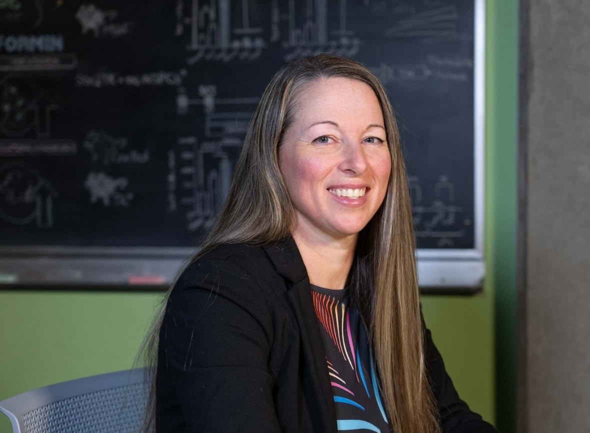 Woman in front of a chalkboard.