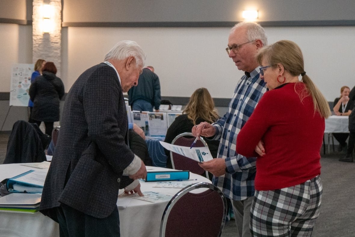 thunder-bay-budget-session-1 People are seen standing in a room, talking.