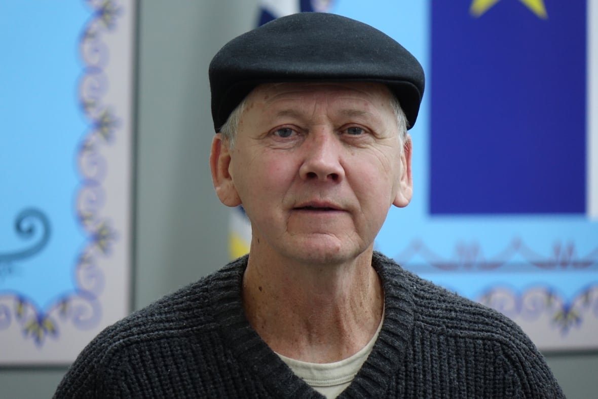 tom-rose A man wearing a hat and a grey sweater.