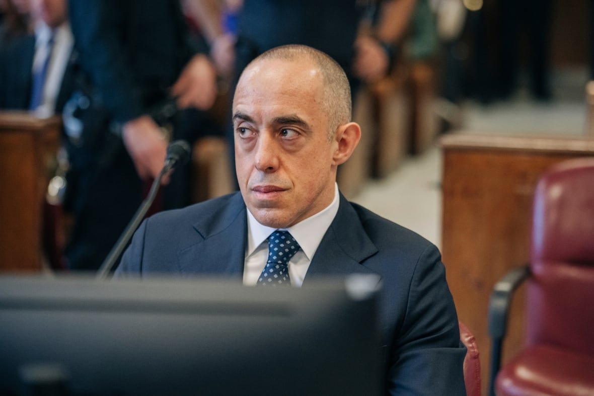 trump-hush-money A bald man in a blue suit and tie sits in a courtroom.