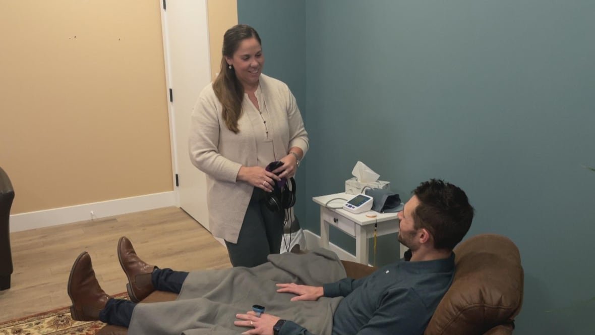 two-person-ketamine A nurse practitioner removes a mask and headphones from a person sitting down.