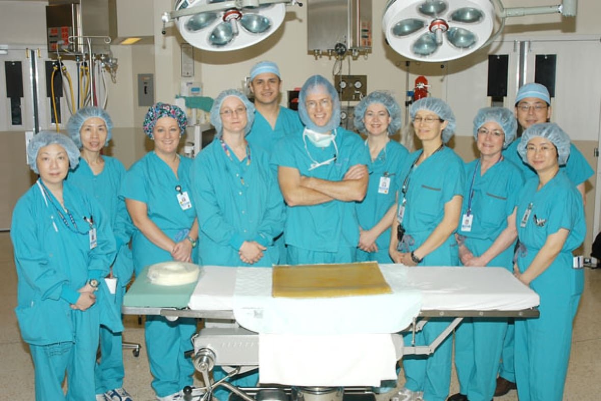 ubc-neurosurgery-team The neurosurgery team at UBC stands in front of a table, wearing blue scrubs, with Dr. Christopher Honey standing in the middle.