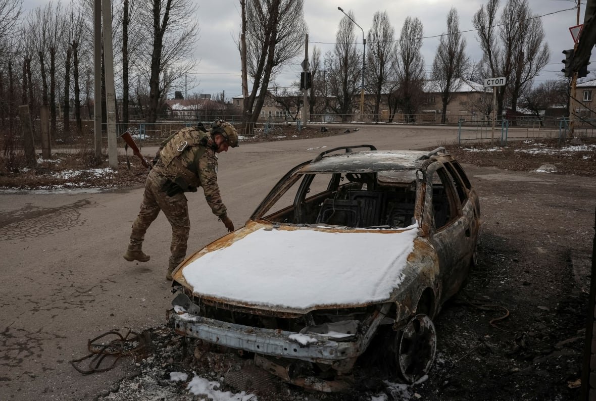 A Ukrainian police office inspects a car in Pokrovsk, Ukraine, which was damaged by Russian military strikes.