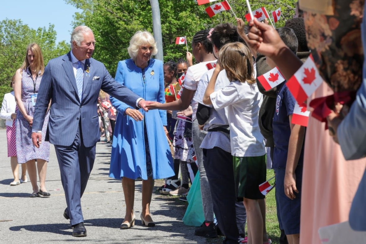 1397957407 Two people greet schoolchildren who are holding Canadian flags.