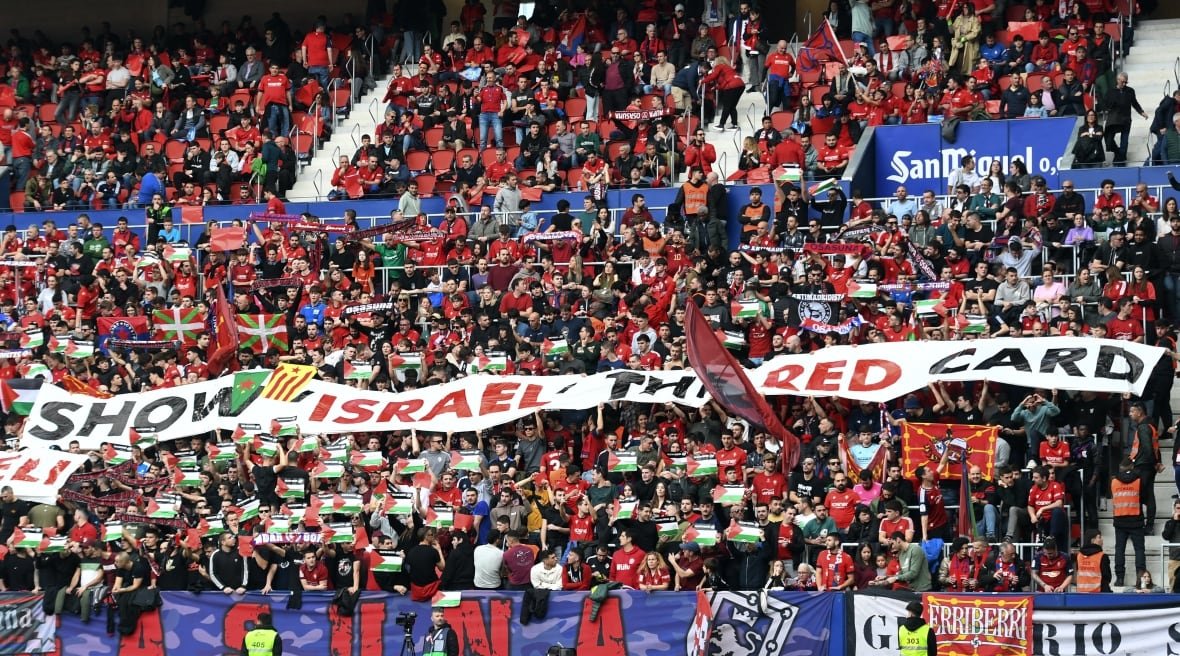 2199086454 Soccer fans unfold a banner reading "Show Israel the red card."