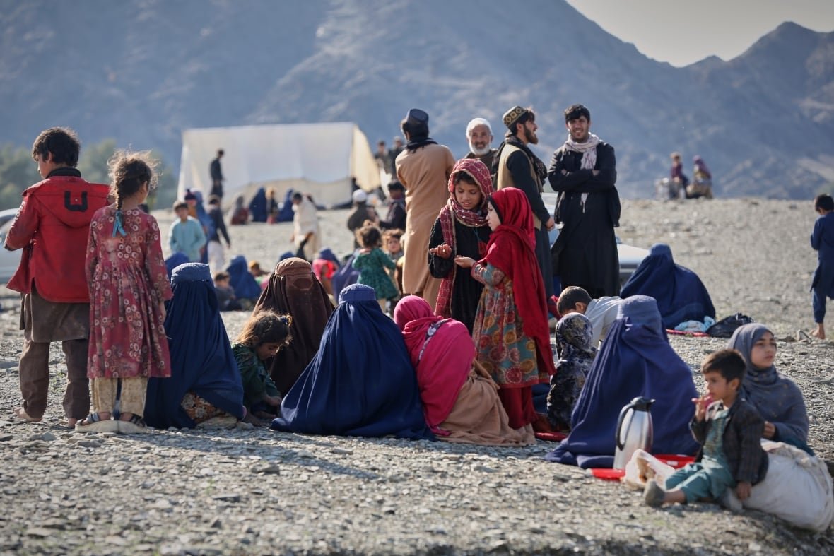 afghanistan-pakistan-2 Men, women and children sit along a border.