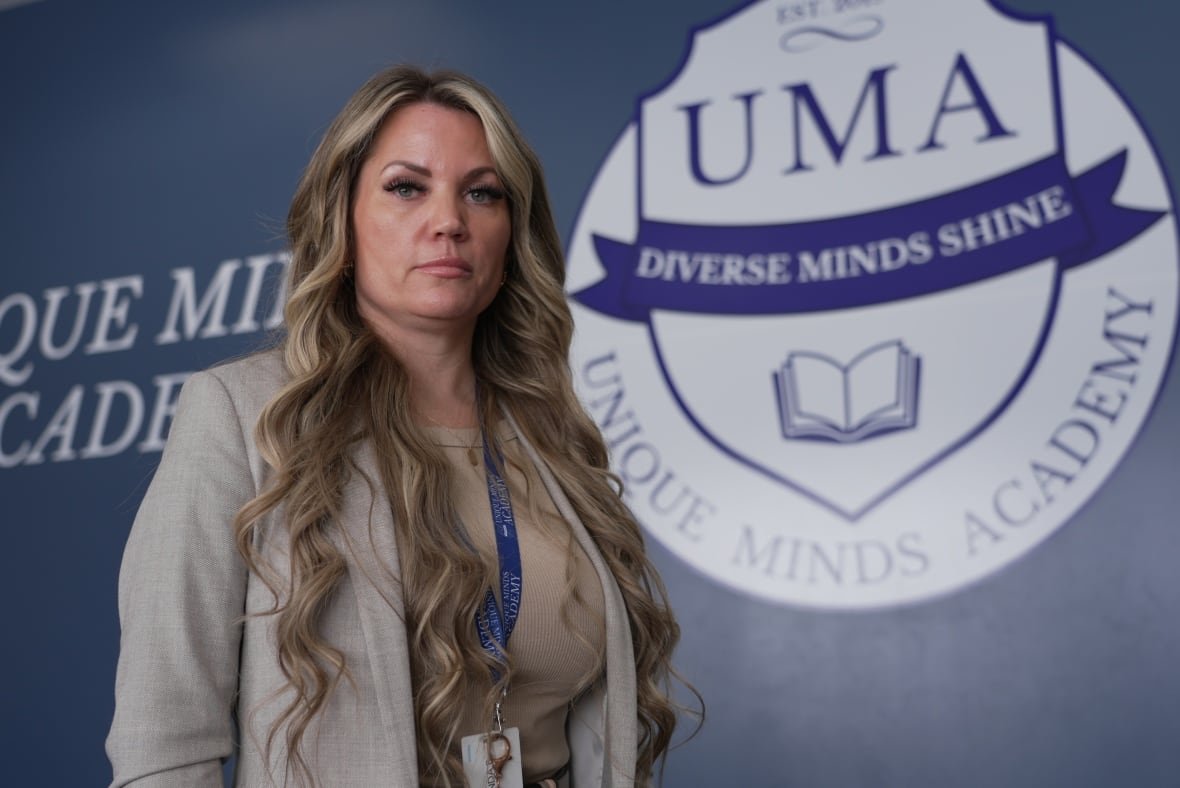 amanda-baysarowich A woman stands in front of a sign that says, Unique Minds Academy.