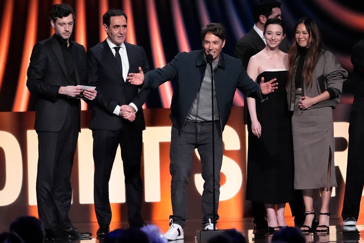 aptopix-2025-film-independent-spirit-awards A person gestures while speaking on stage as others surround them.