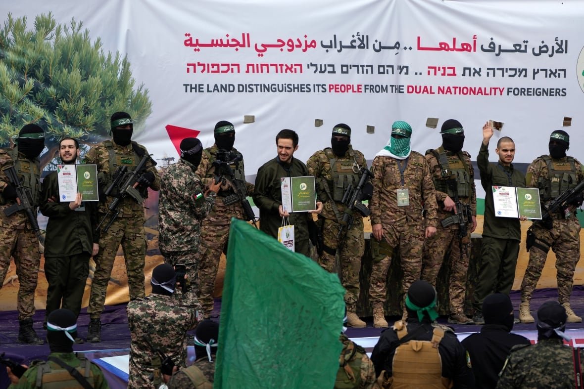 People holding up booklets are seen on stage surrounded by armed guards.