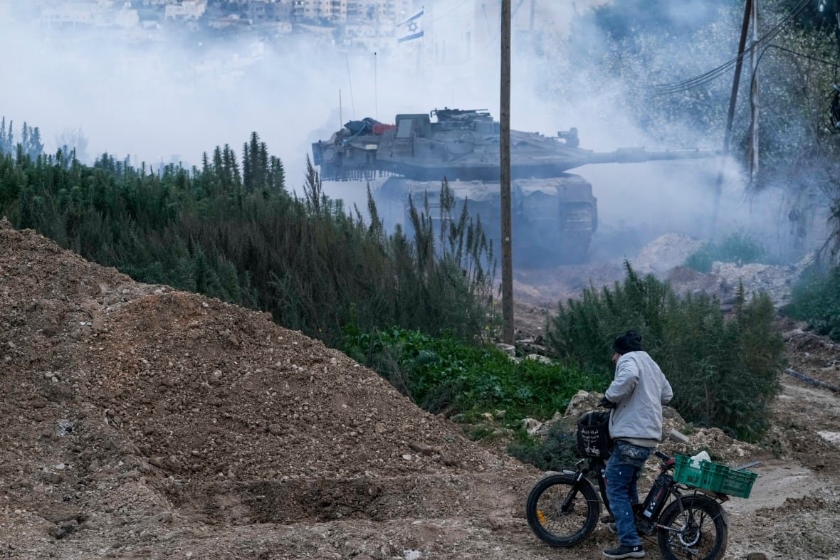 aptopix-israel-palestinians-3 A person on a bicycle looks at an approaching tank.