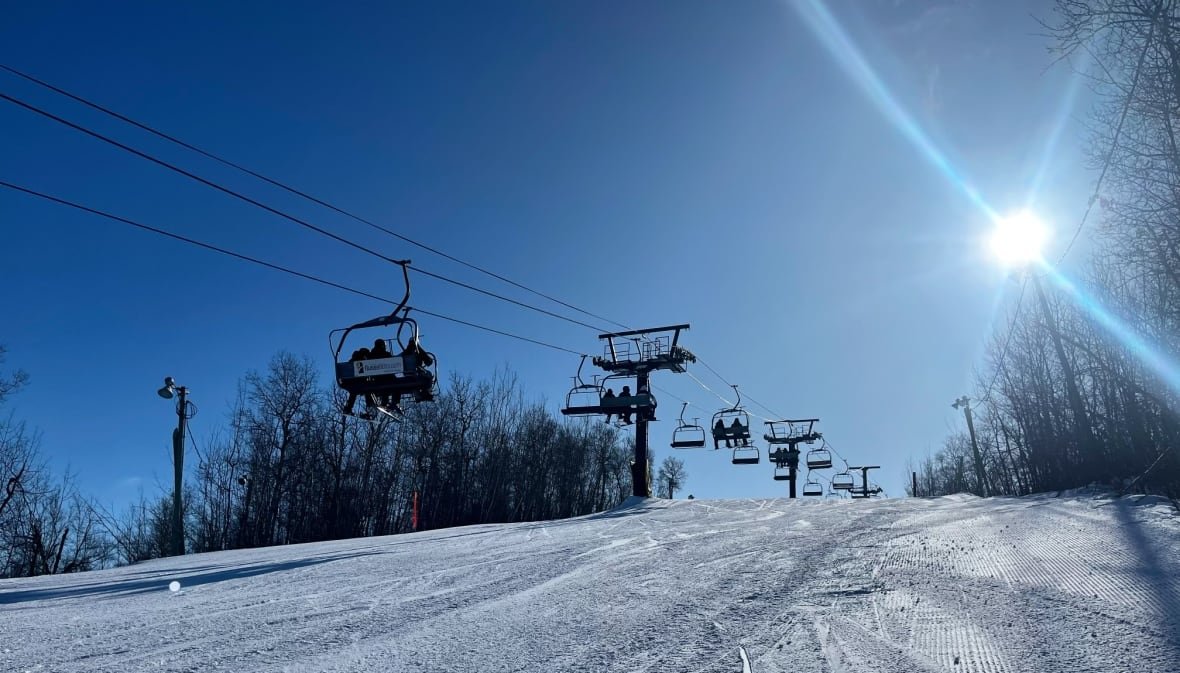 A chair lift carries skiers up a hill.