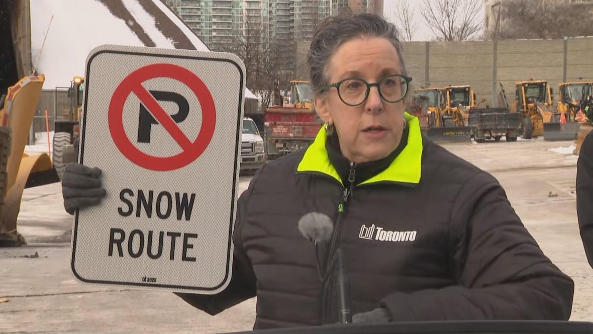 Woman holding a road sign that designates a snow route