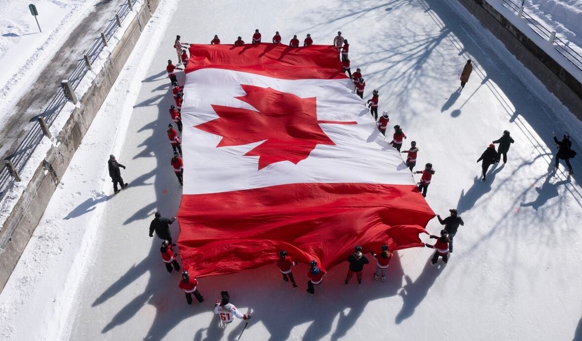 canadian-flag-20250214 People on ice unfurl a Canadian flag on the Rideau Canal Skateway