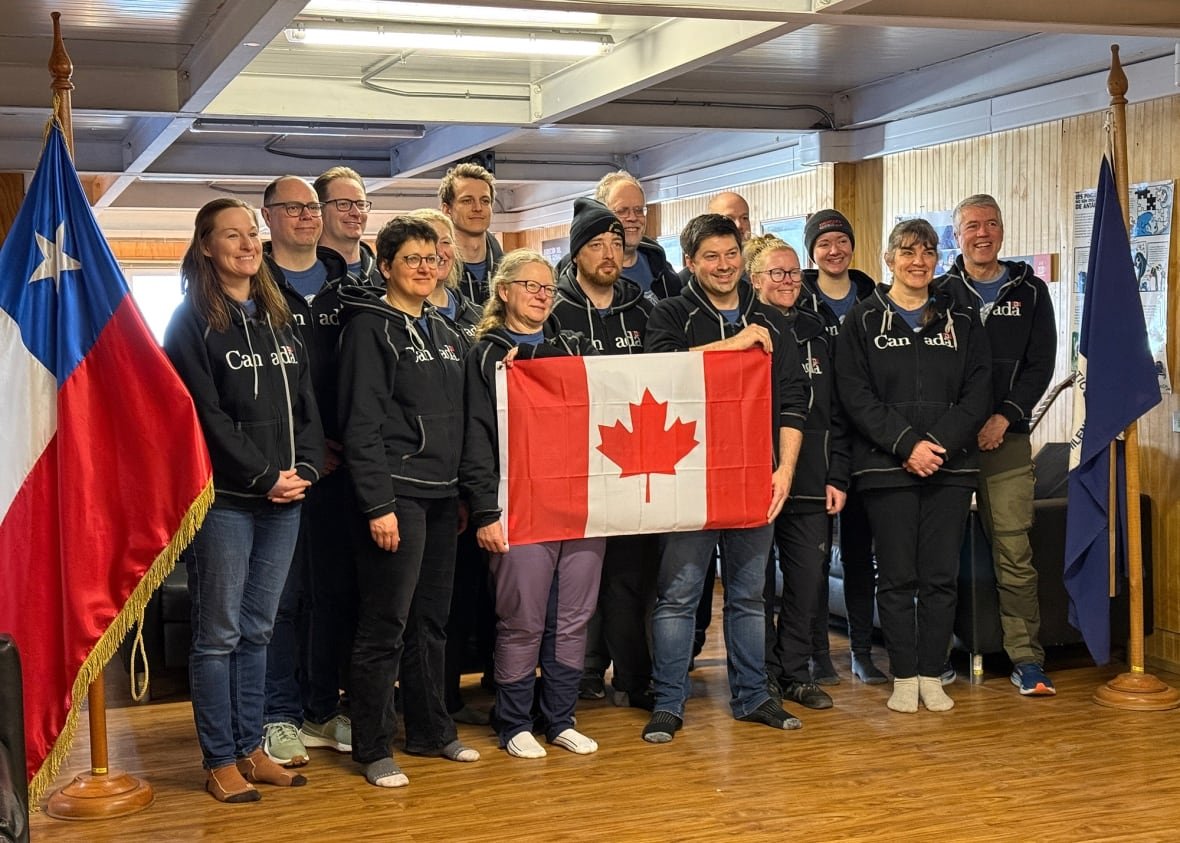 canadian-scientists-at-chilean-base-in-antarctica A bunch of people wearing black Canada sweatshirts pose for a photo.