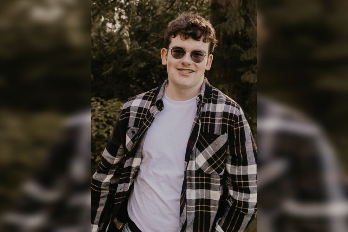 chase-de-balinhard-2 A teen boy smiles for the camera. He has short brown, curly hair and is wearing sunglasses and a plaid buttondown over a white T-shirt.