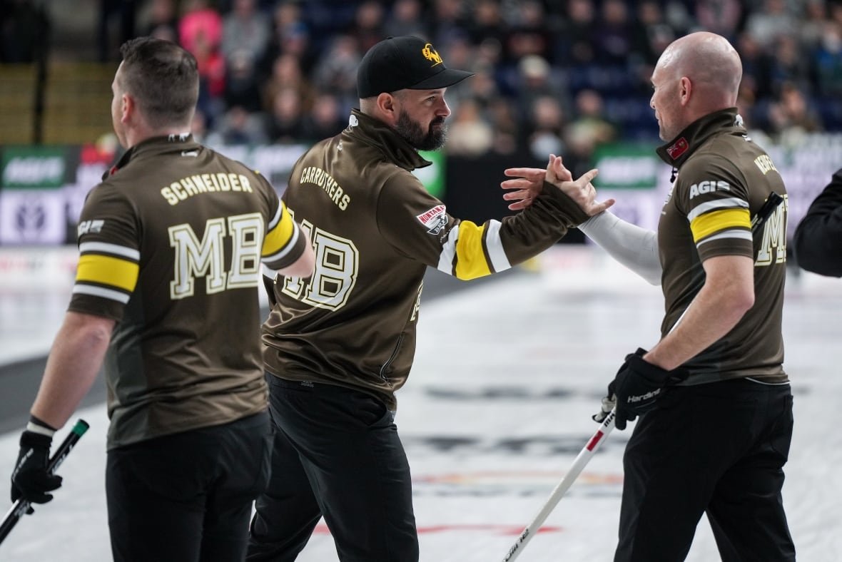cur-brier-20250307 Two curlers dressed in black and brown clasp hands.