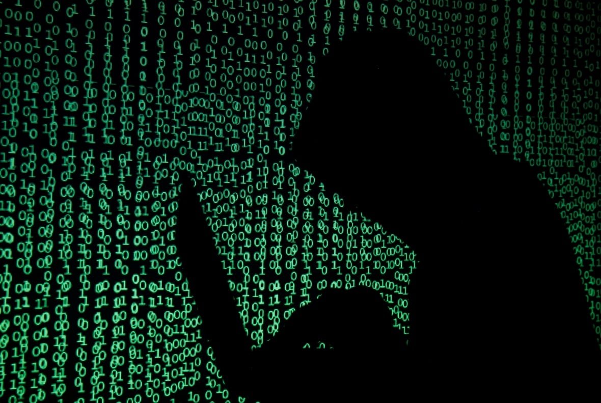 cyber-attack A silhouetted man hunched over a computer with data illuminated in the background.