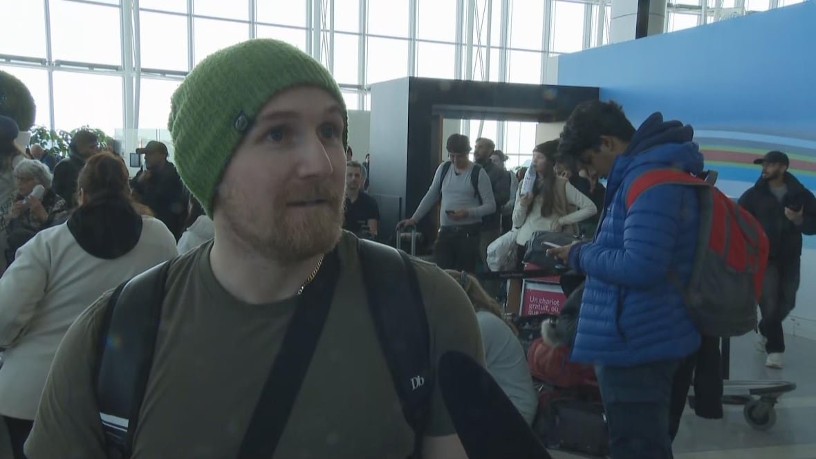 dan-milewski Photo of a man in a green tee shirt and green beanie in a crowded airport.