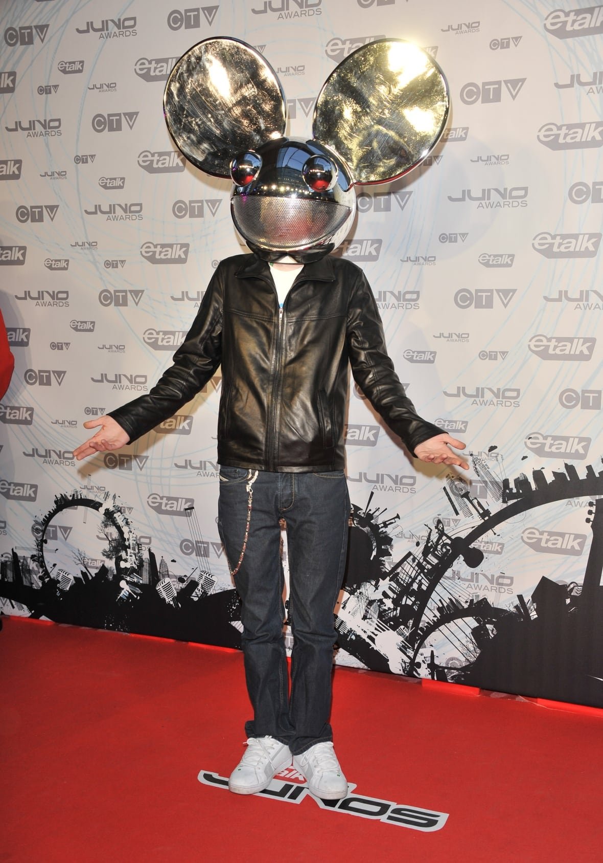 Deadmau5 on the red carpet wearing jeans, a black leather jacket and silver helmet with mouse-ears.