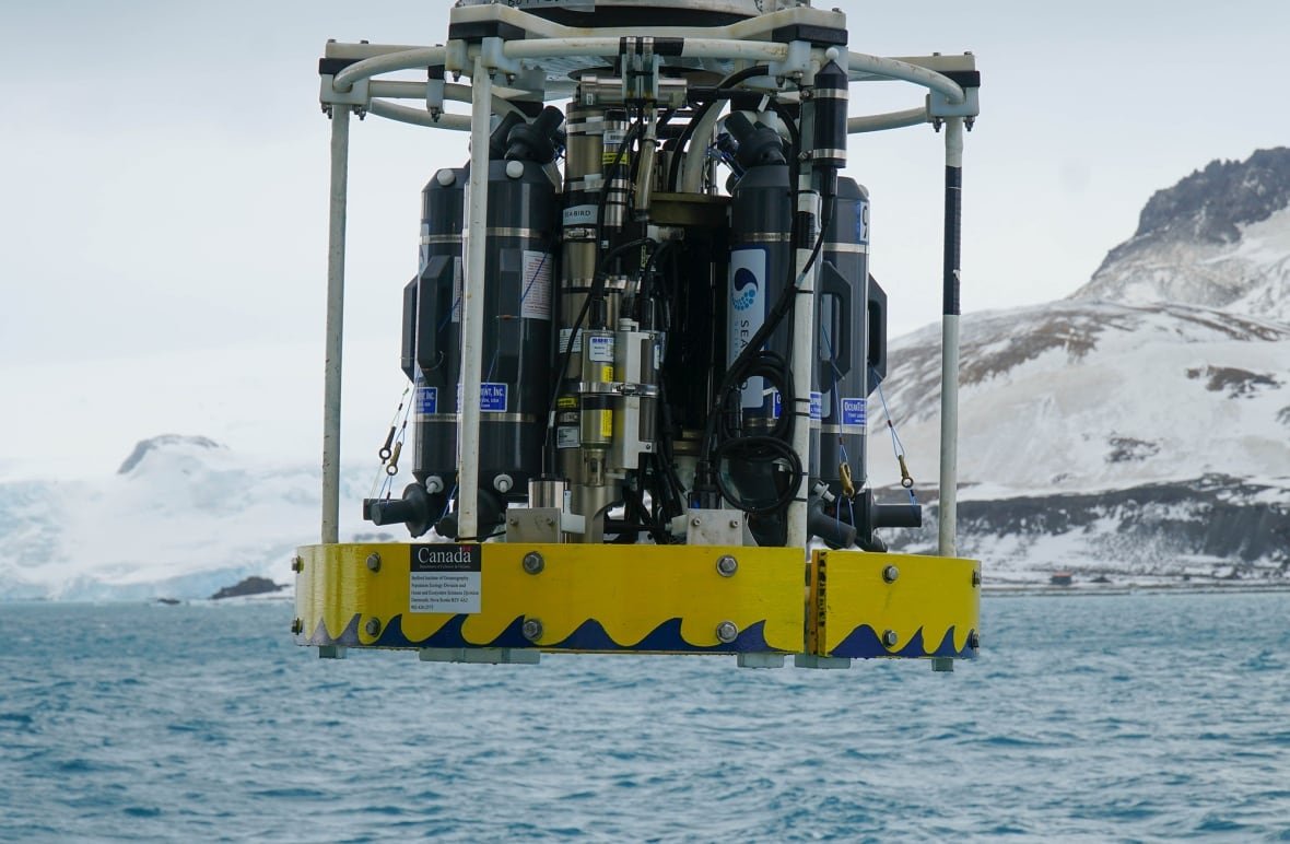 deception-island-ship A winch on a ship, with a person standing next to it, looking out onto the water.