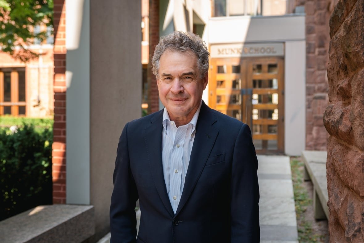 drew-fagan-professor-at-munk-school-of-global-affairs-and-public-policy Man in a suit standing outside in front of a building.