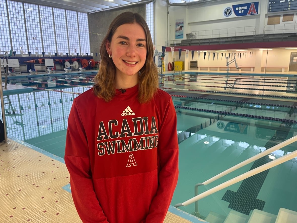 ella-collins Woman in red sweater stands near swimming pool