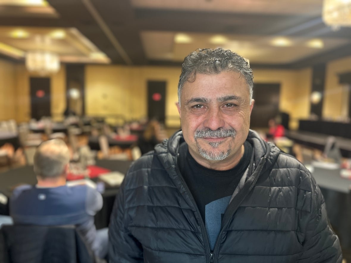 emile-nabbout A man smiles in a large conference room, which is blurred behind him.