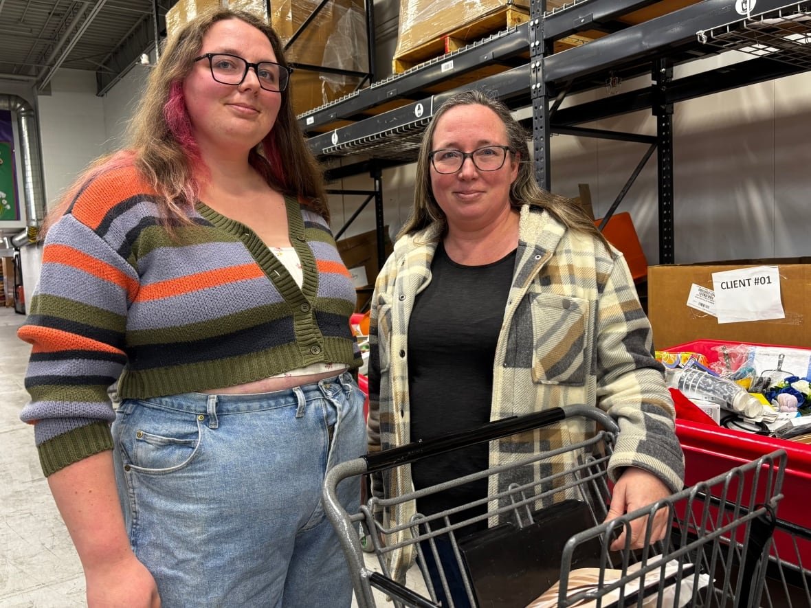 emma-york-and-alex-heuvel Two women smile at the camera behind a shopping cart.