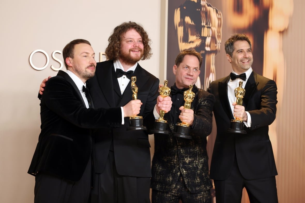 flow Four men smile and pose with trophies.