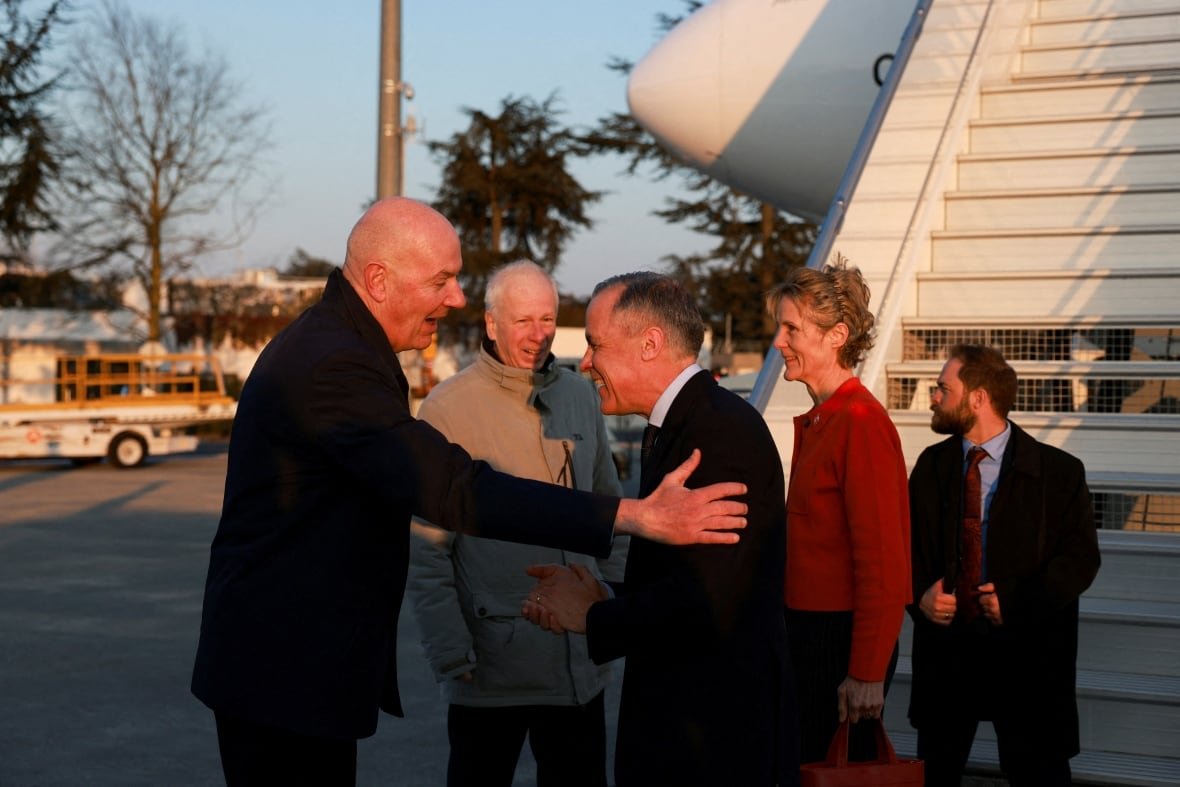 france-canada two men shake hands outside of a plane