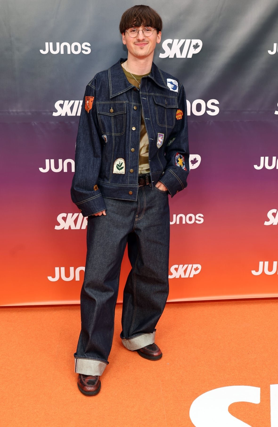 Fredz on the red carpet wearing a dark denim jacket and jeans.