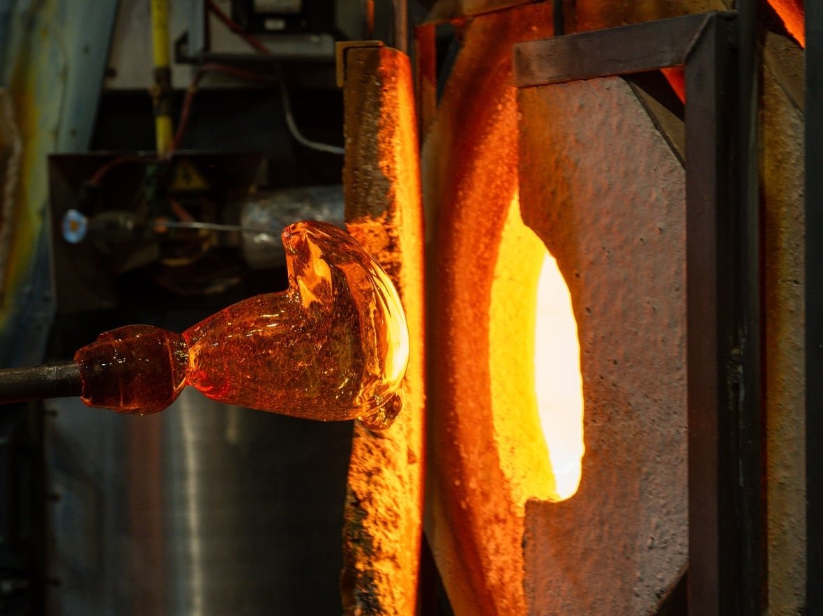 A blob of glass is pulled from an oven.