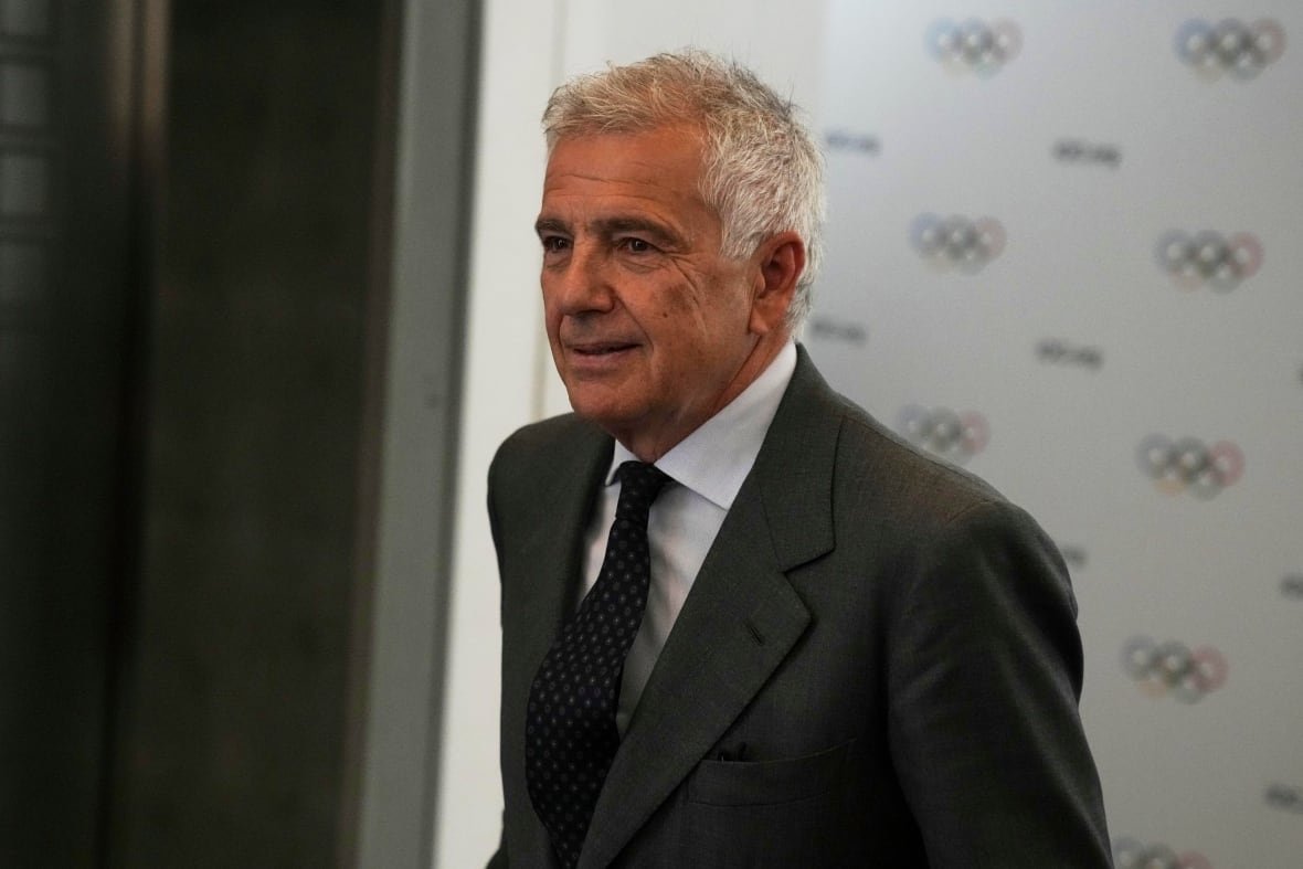 greece-olympics-ioc-election-7 A man in a suit walks, looking off-camera.