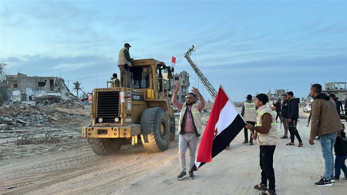 heavy-machinery-gaza-1 People stand next to construction machinery with an Egyptian flag.