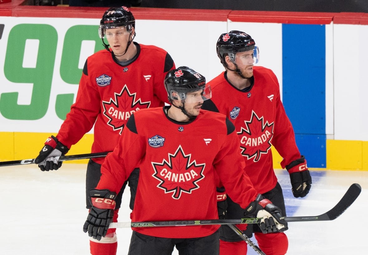 Three men's hockey players stand on the ice.