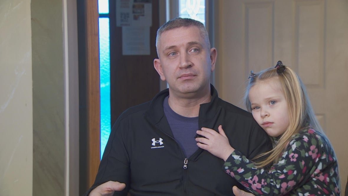 ihor-and-daughter A man is pictured sitting in a chair with a young girl hugging him on the side.