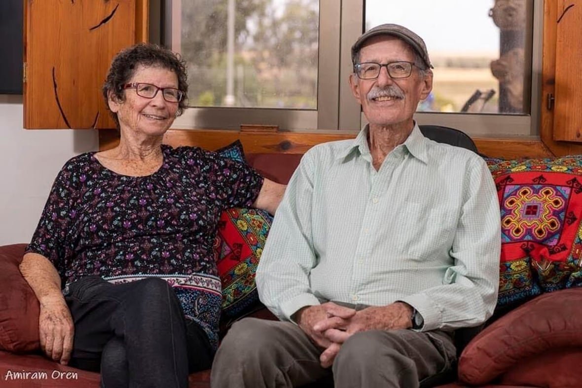 An elderly man and woman sit on a couch.