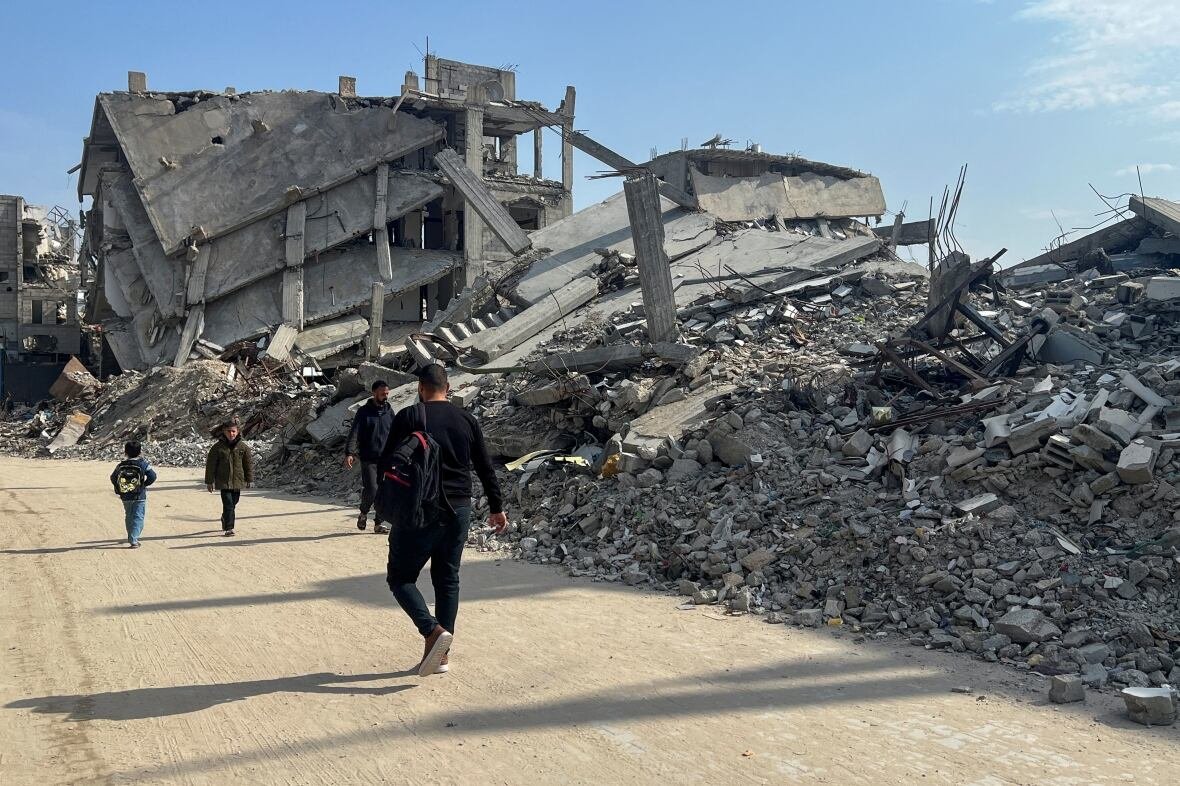 israel-palestinians-gaza-trump-reax People walk past rubble.