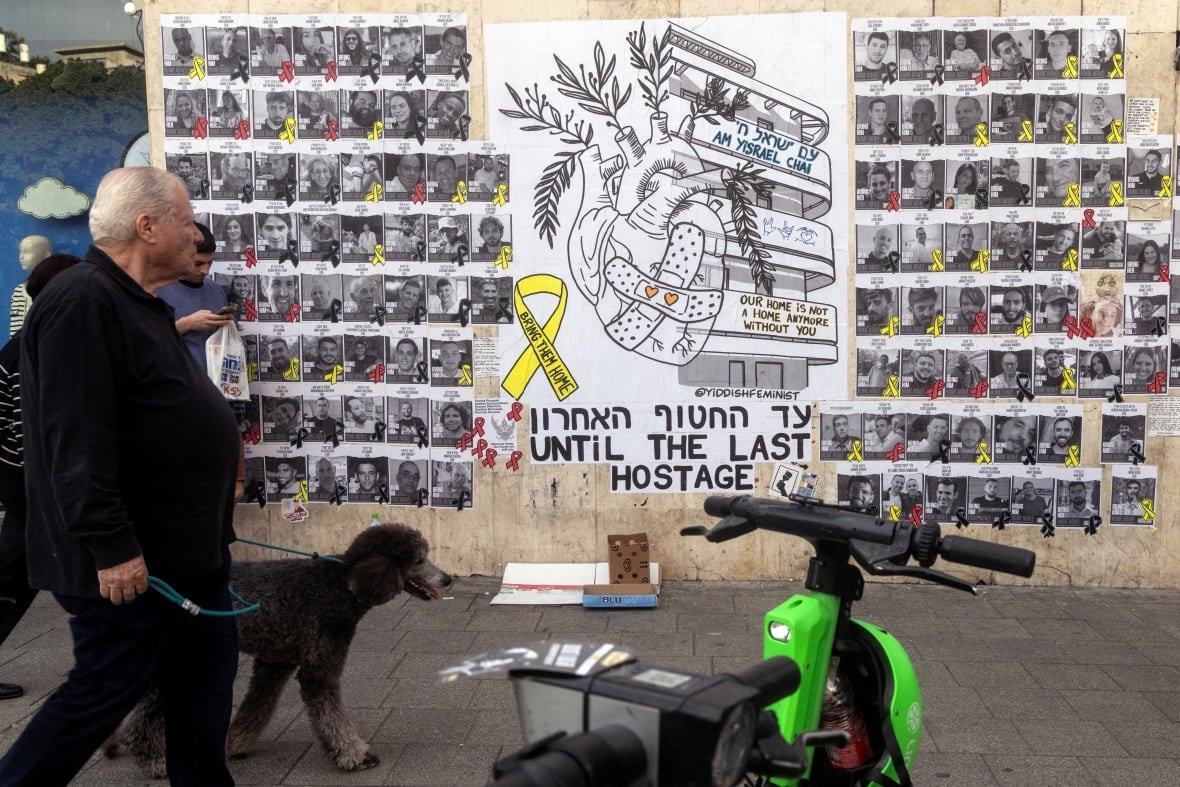 israel-palestinians-hostages People walk next to a graffiti supporting the release of all hostages who have been held in Gaza.